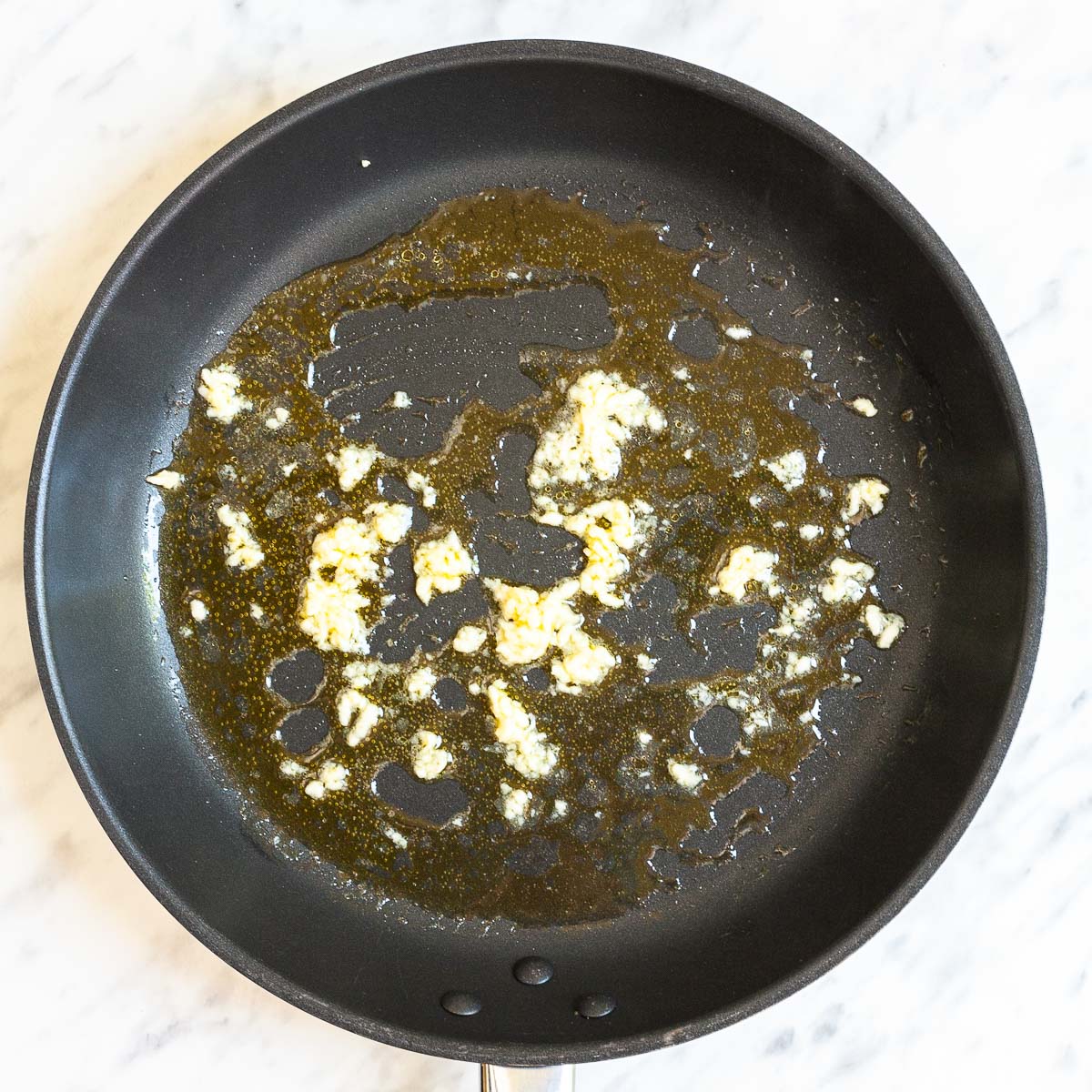 Minced garlic and melted butter in a black frying pan