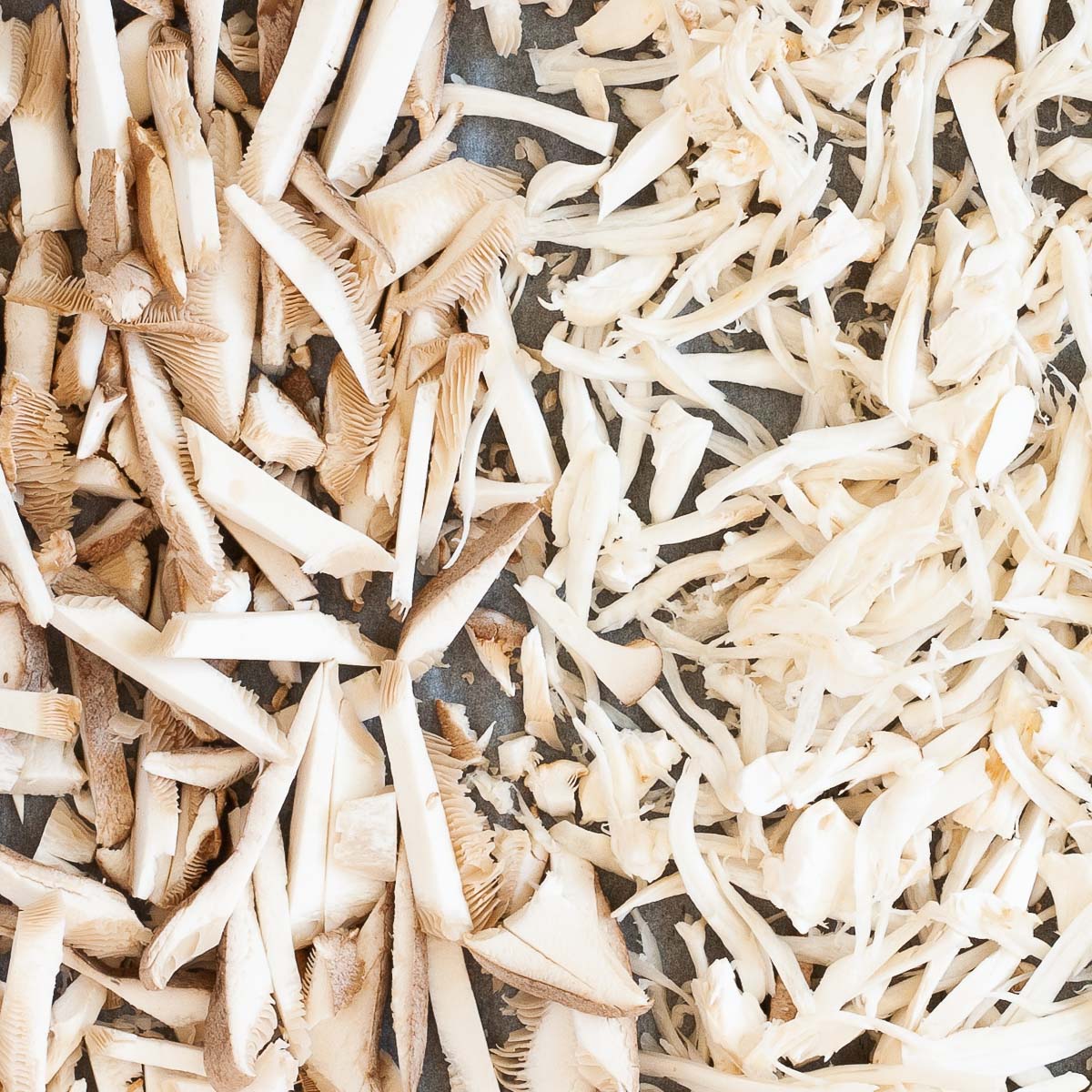 A parchment paper is full of white shredded mushrooms.