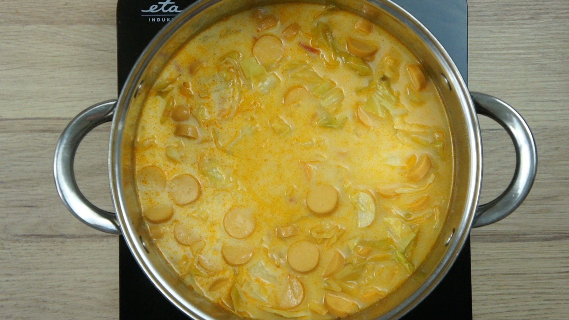 Orange creamy soup with cabbage and vegetables in a stockpot.