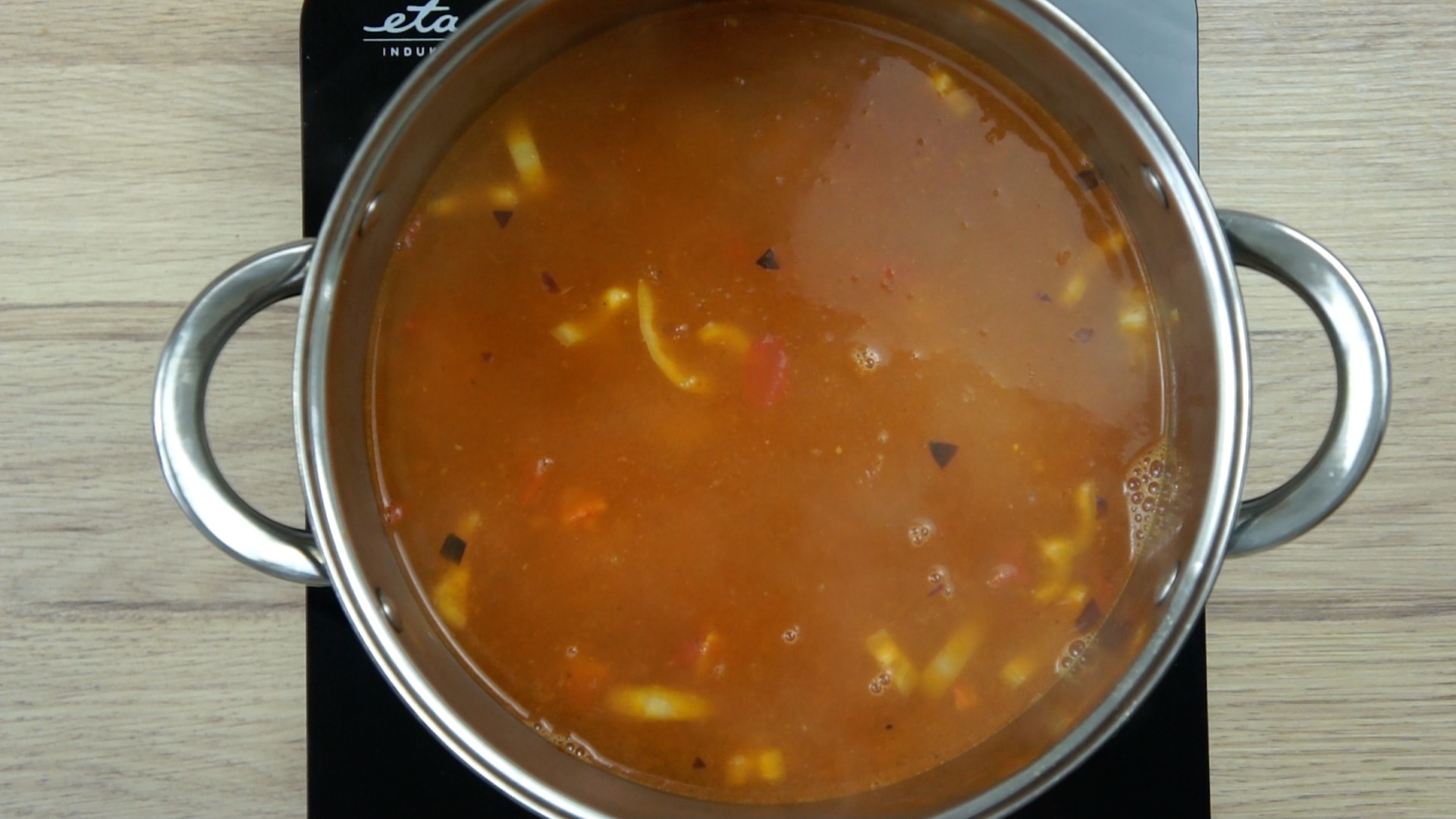 Brown stock in a stockpot with vegetable bits.