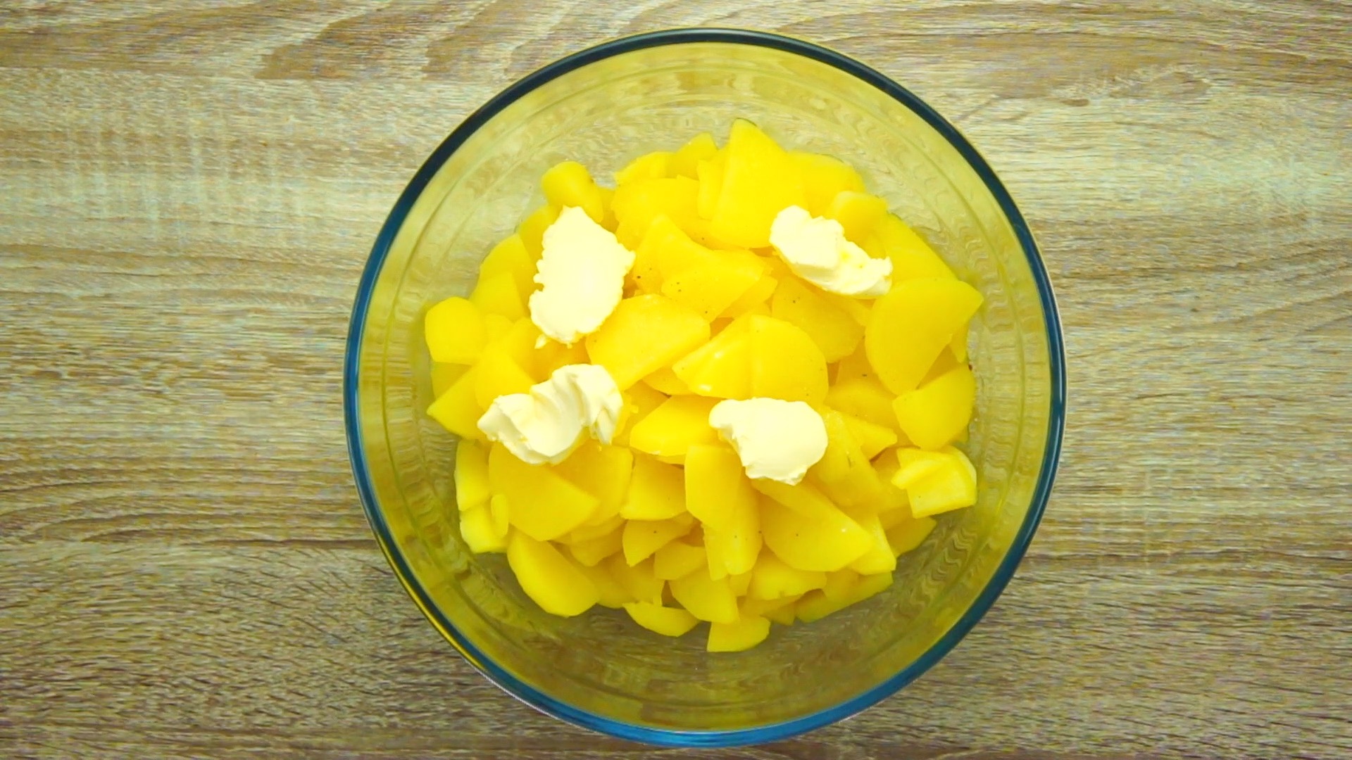 Glass bowl with soft cooked diced potatoes and 4 tablespoons of butter