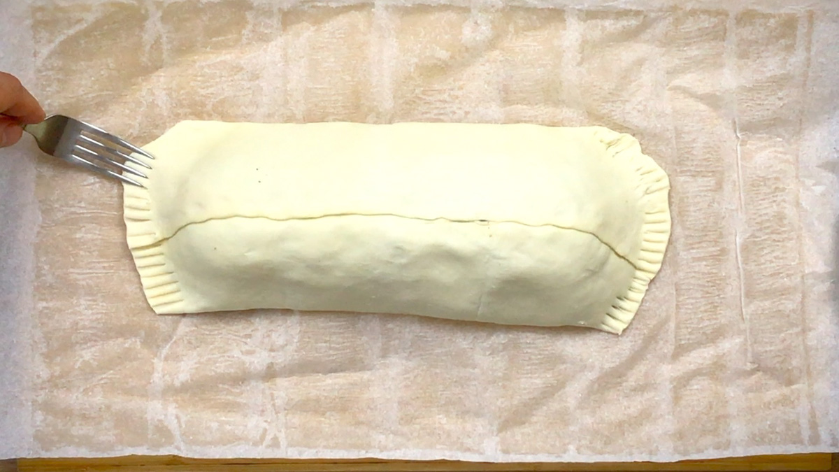 A parchment paper with a rectangle shaped filled puff pastry