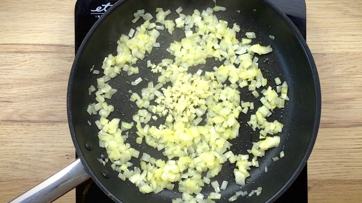 Black frying pan with minced onion and galric.