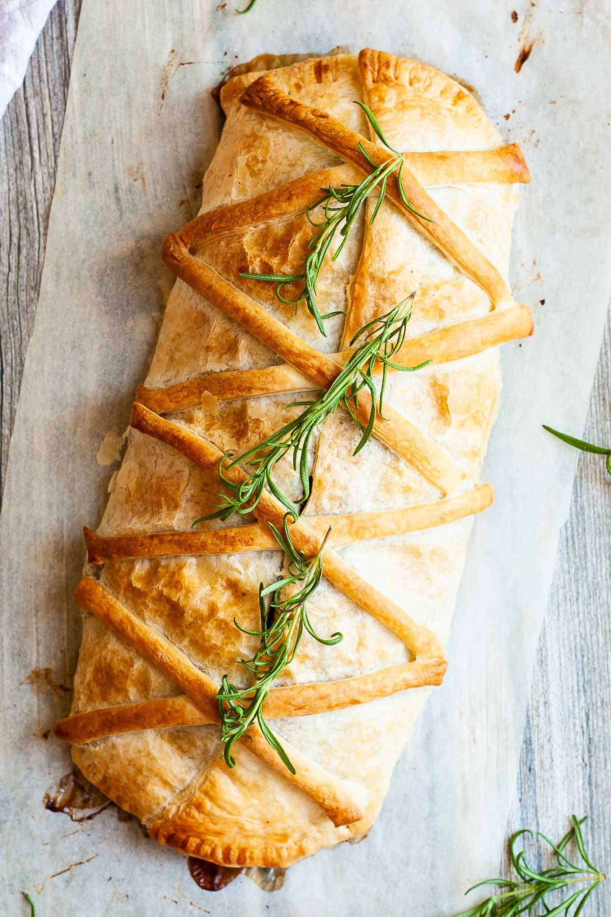 Rectangle shaped yellow brownish baked puff pastry from above with green herb leaves on top