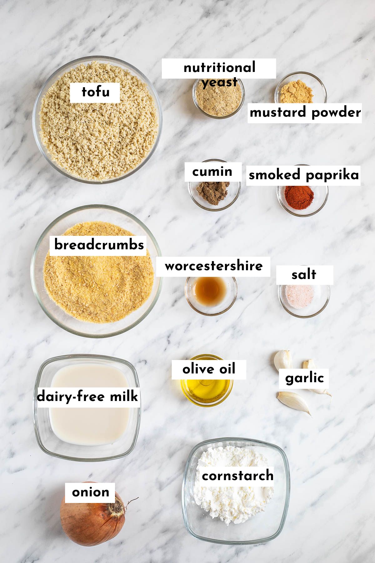 Ingredients of tofu burger in small glass bowls like tofu mince, breadcrumbs, milk, cornstarch, and different spices.