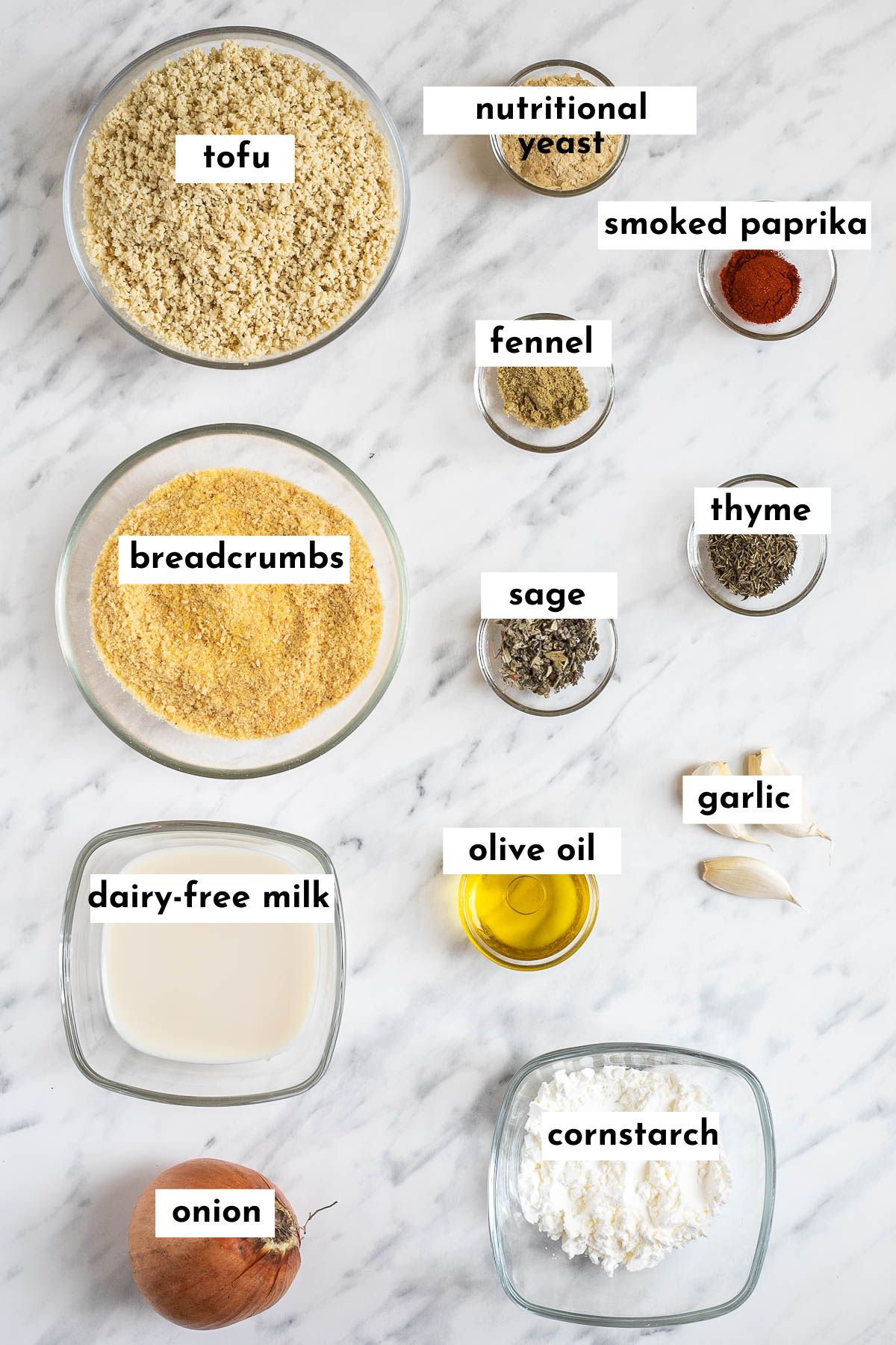 Ingredients of vegan breakfast sausage patties are placed in small glass bowls like tofu mince, breadcrumbs, milk, white powder, and various colorful spices.