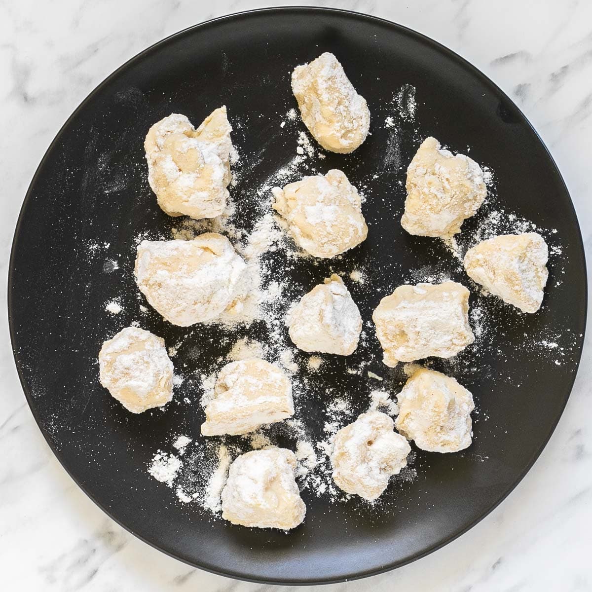 Breaded cauliflower florets on a black plate.