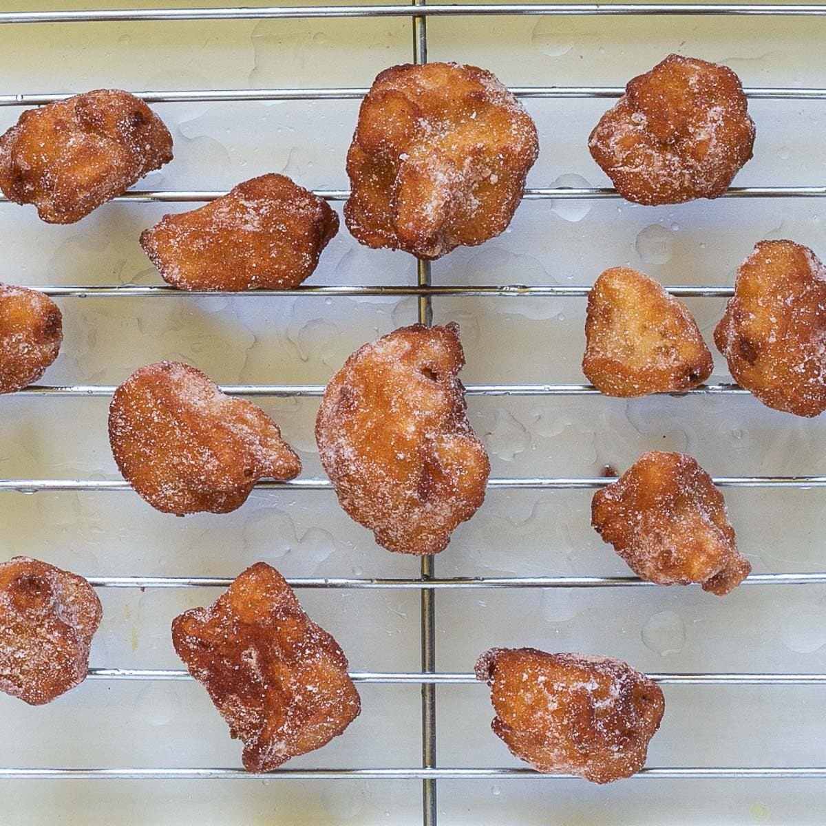 Crispy breaded deep-fried cauliflower florets are placed on a grill rack.