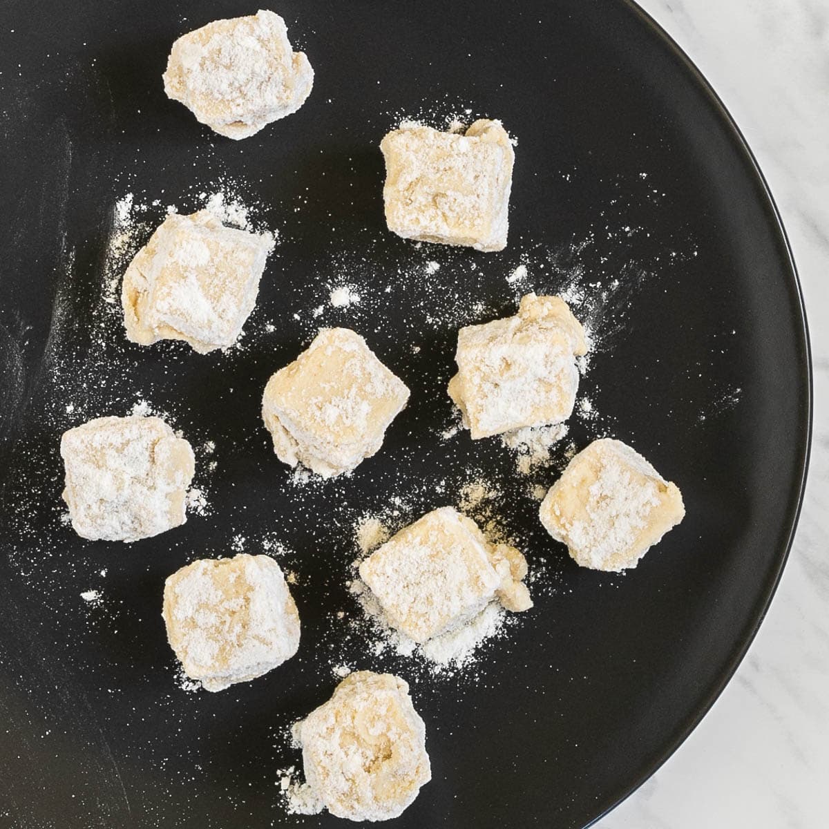 Breaded tofu cubes on a black plate.