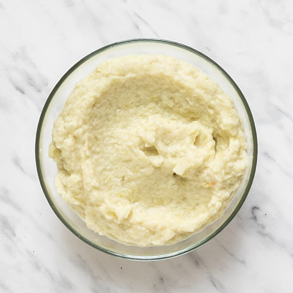 Glass bowl with a light yellow onion puree.