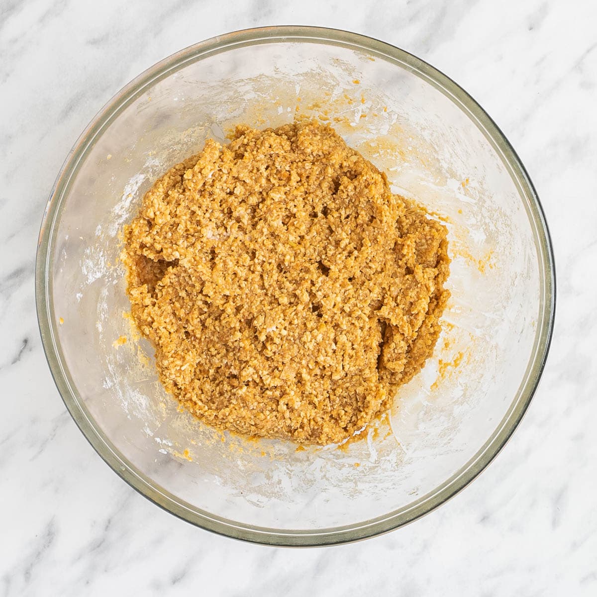 A sticky light orange dough in a glass bowl.