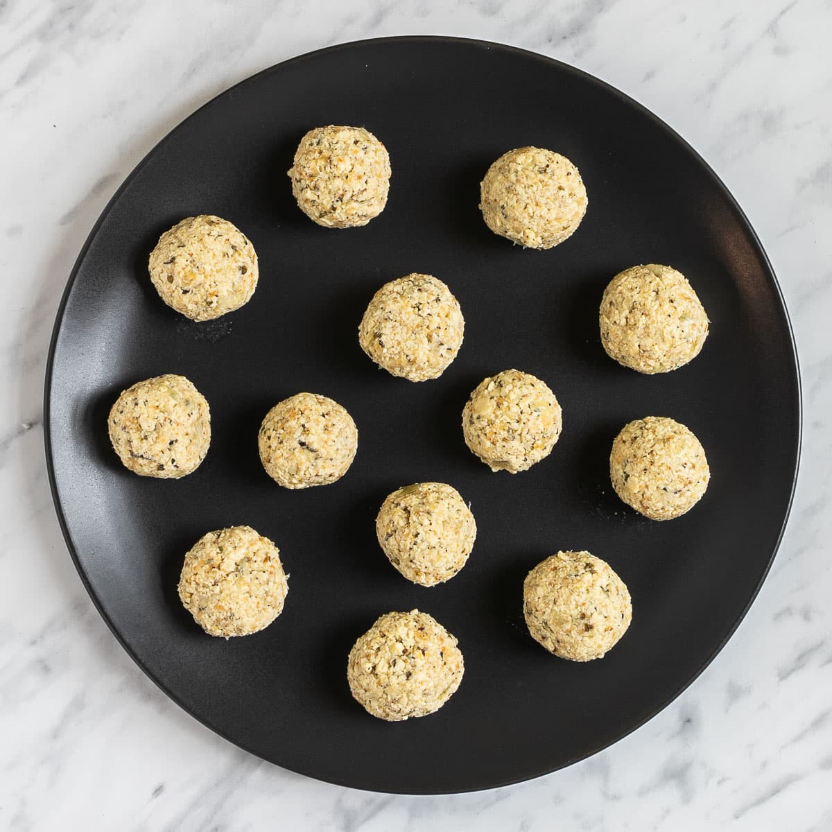 Black plate with several uncooked tofu balls.