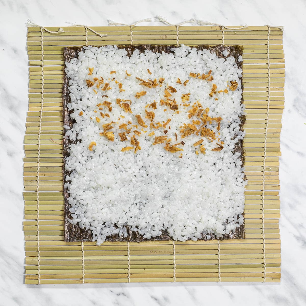 Bamboo mat with seaweed sheets, rice and crispy fried onions. 