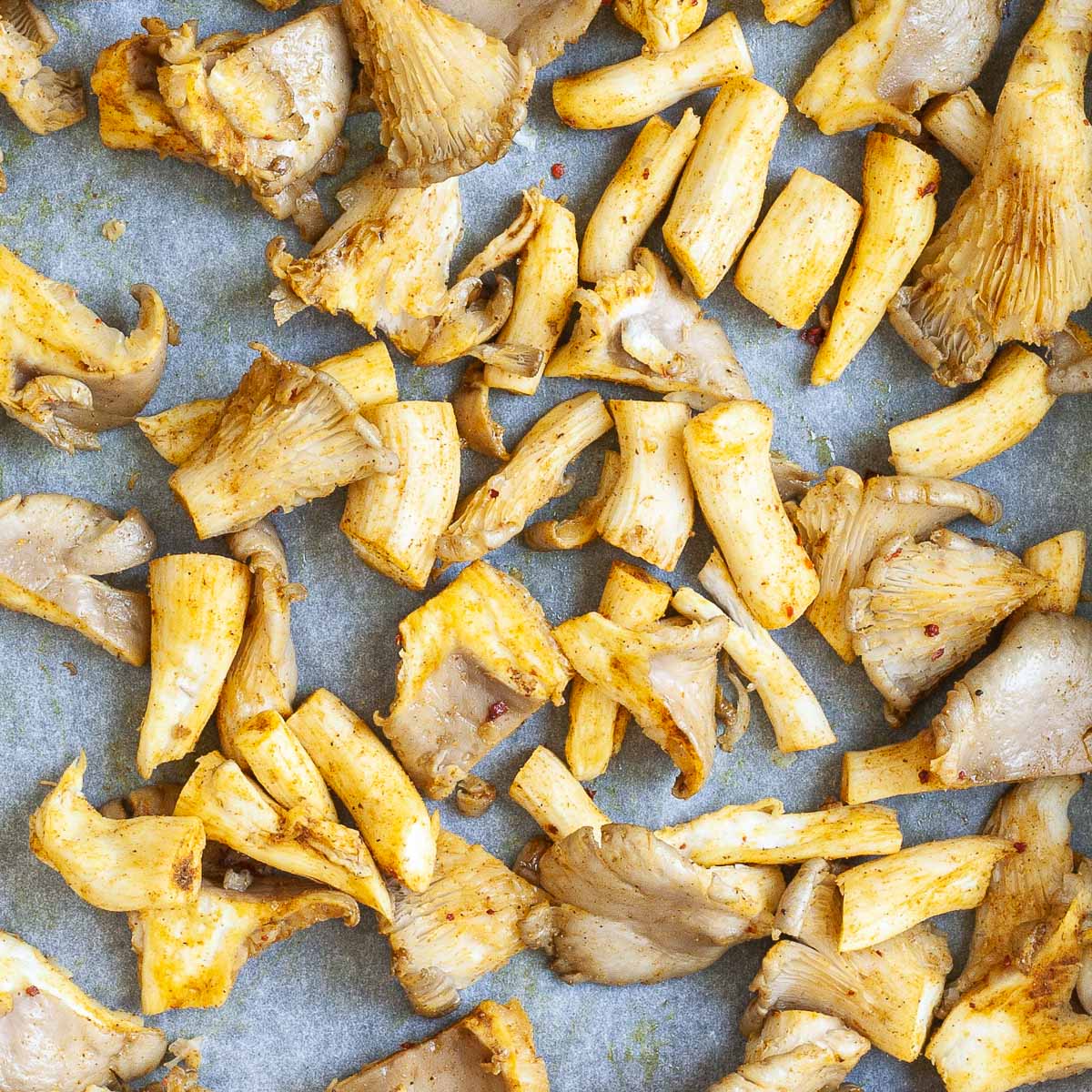 Yellowish raw mushroom shreds on a parchment paper.