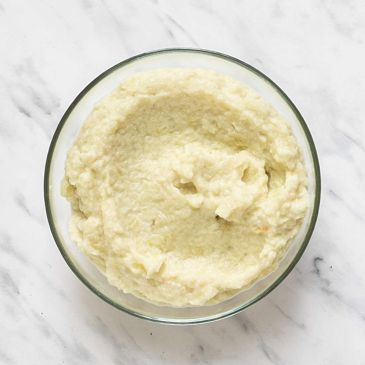 Glass bowl with a light yellow onion puree.