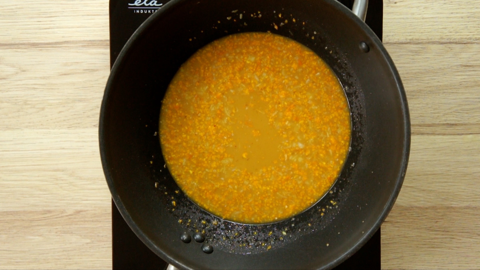 Orange sauce with grated ginger and garlic pieces in a wook