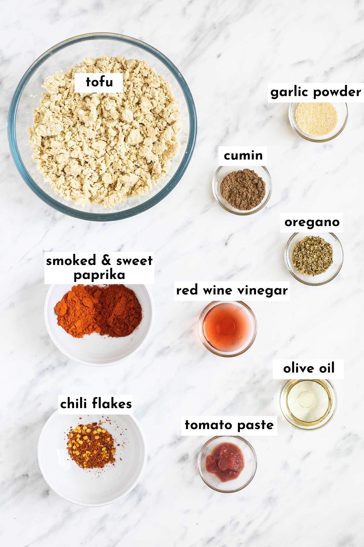 The ingredients of chipotle plant-based chorizo are in small glass bowls like tofu crumbles, and different spices, vinegar, tomato paste, and oil.