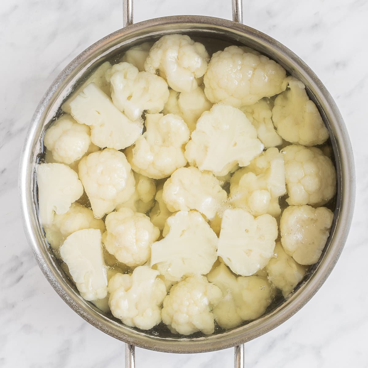 A large stockpot with water and fresh cauliflower florets