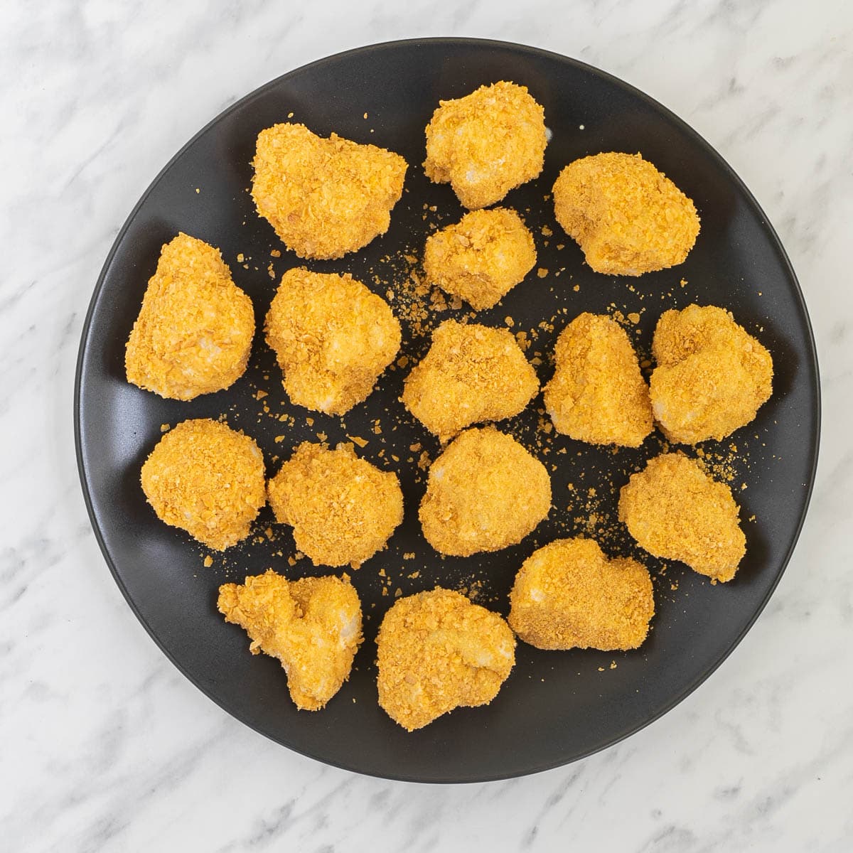 Black plate with breaded cauliflower florets.