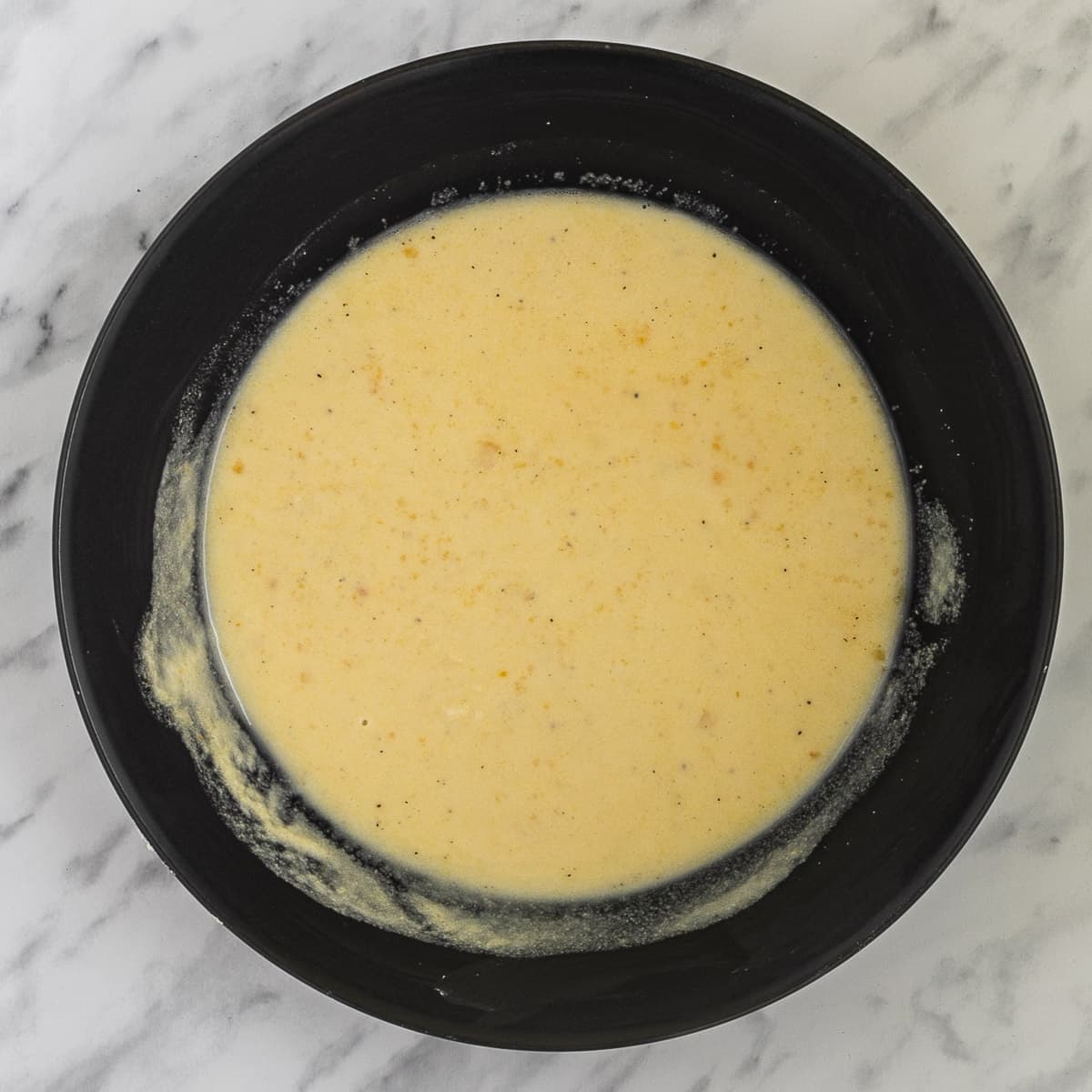 Light yellow wet batter in a black bowl