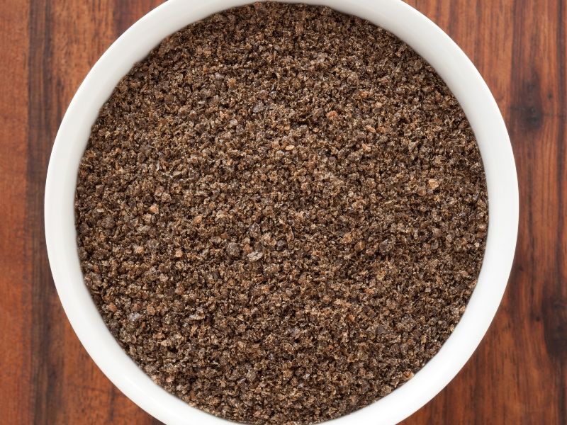 A white plate with dark brown ground chia seeds