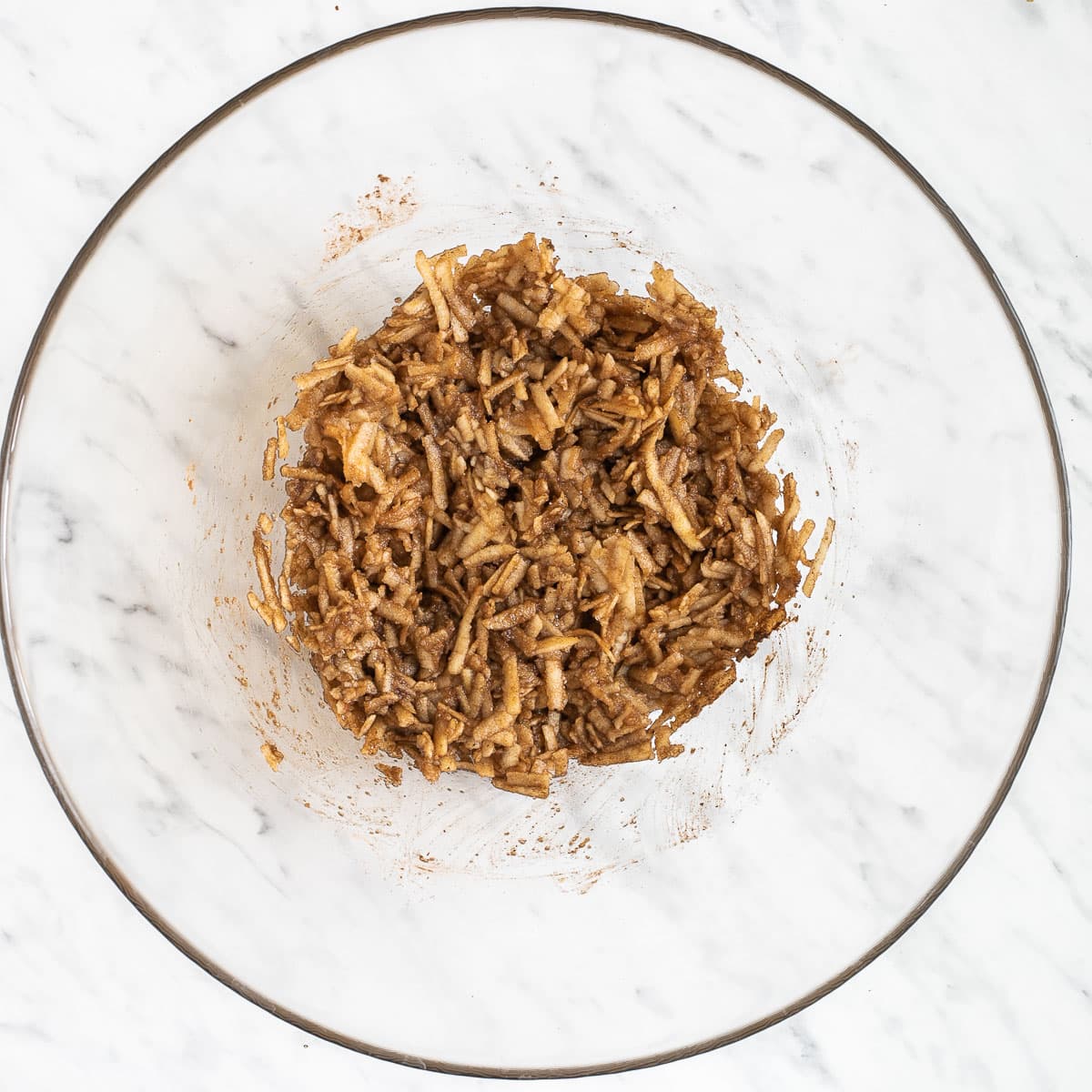 Brown grated apples in a glass bowl.