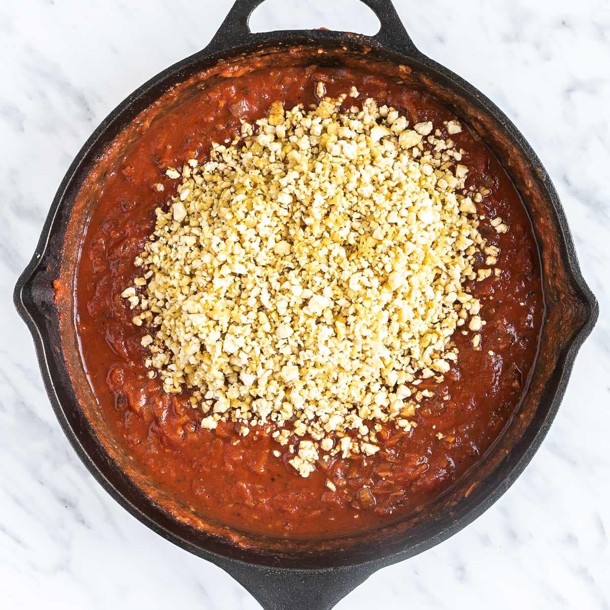 Red chunky sauce with tofu mince on top in a cast iron skillet