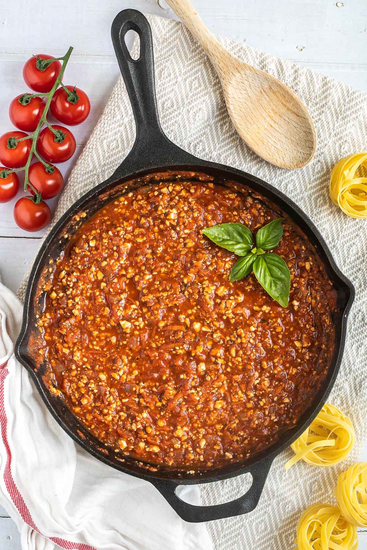 A cast iron skillet with tofu mince in bolognese sauce.