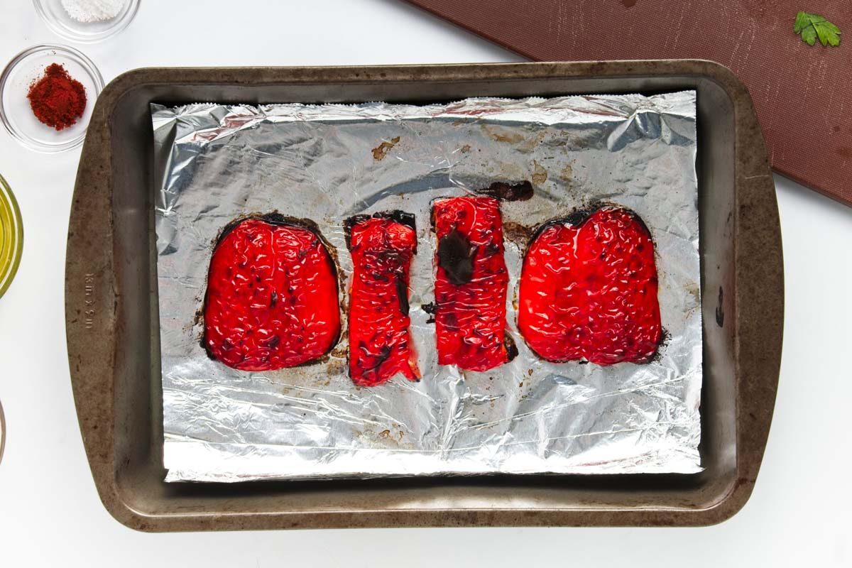 Red pepper slices charred on the edges on a tin foil