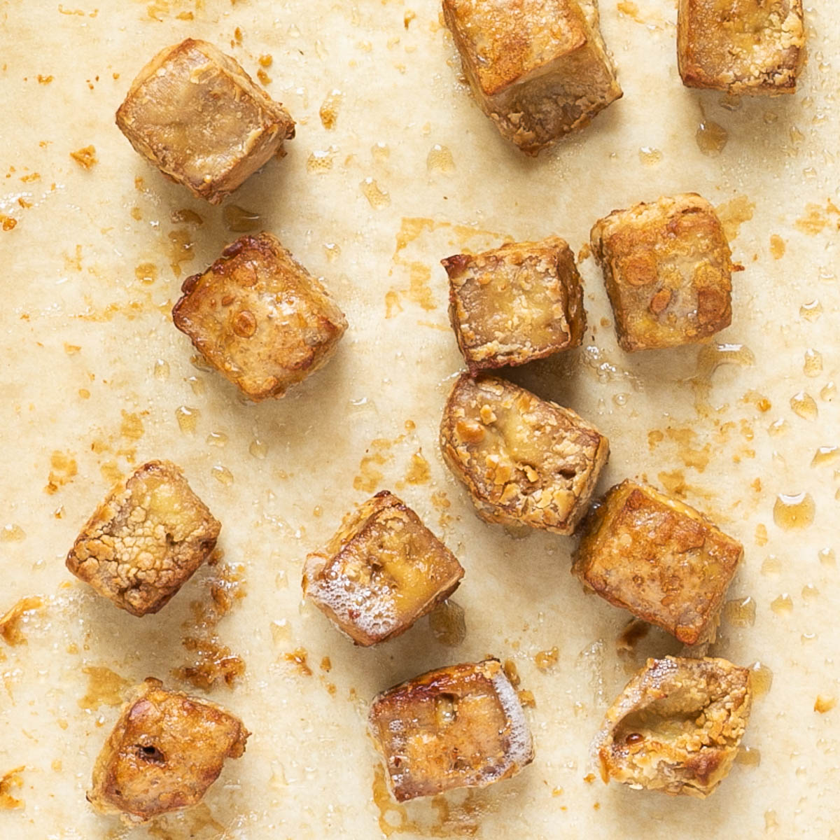 Light brown tofu cubes on a parchment paper.