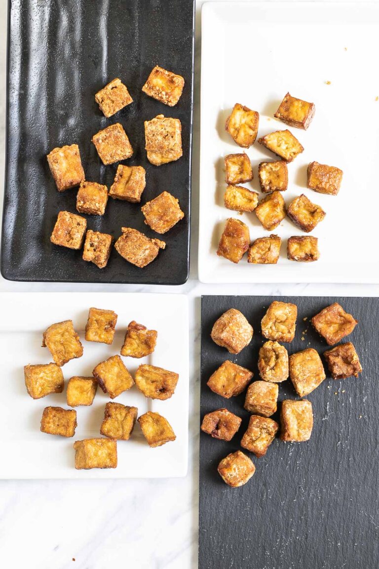 Crispy brown tofu cubes on 4 different plates of white and black.
