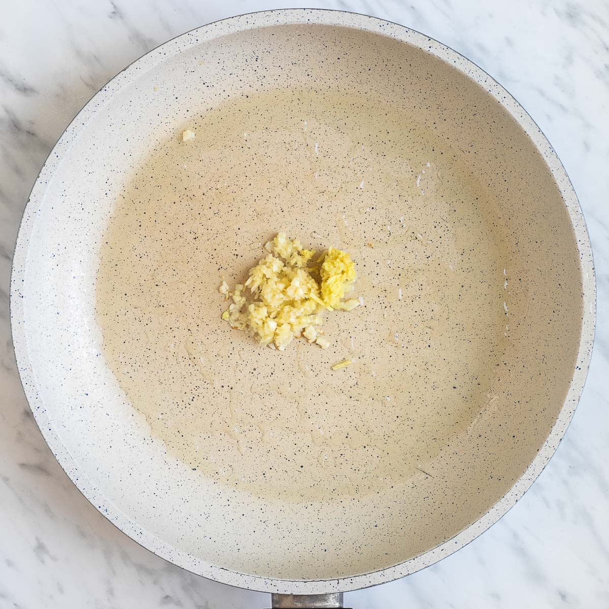 Minced ginger in a white frying pan.