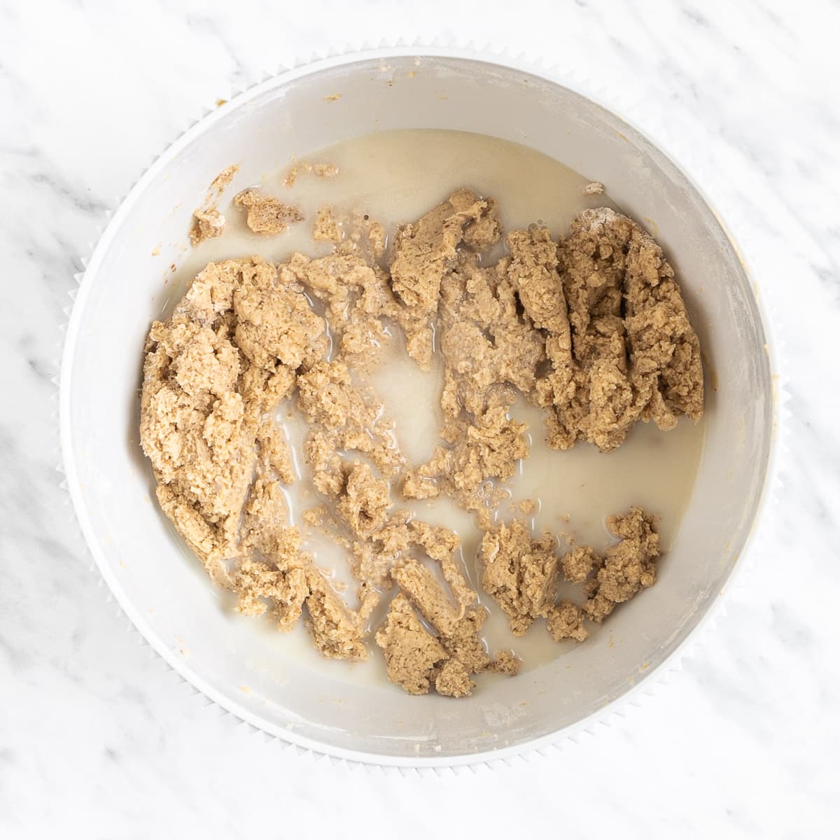Light brown batter with milk in a white bowl.