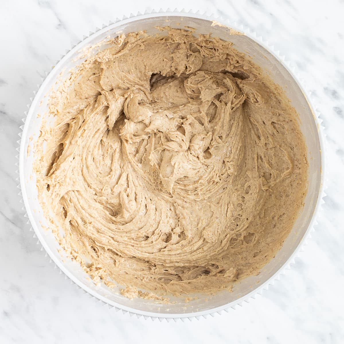 Soft creamy light brown batter in a white bowl.