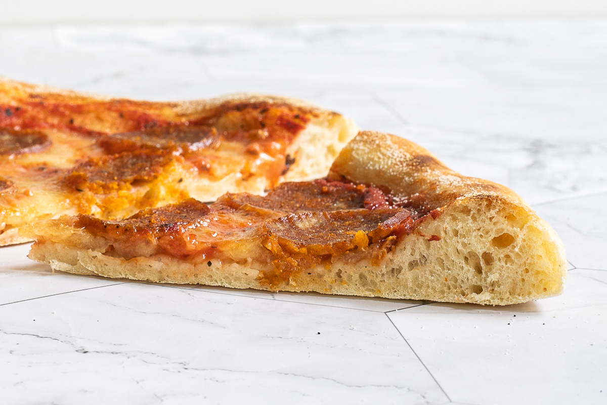 A slice of pepperoni pizza from the side