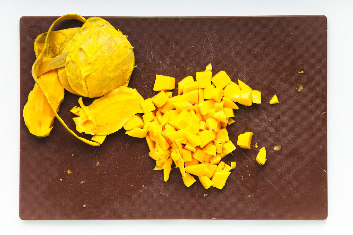 Peeled and diced mango on a brown cutting board.