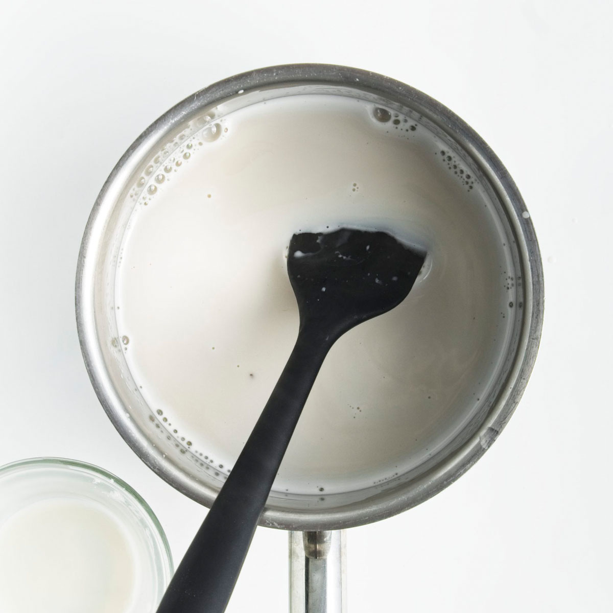Saucepan with white liquid and a spatula