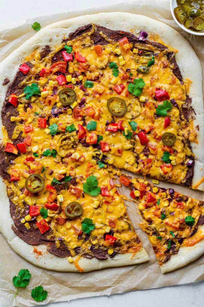 Pizza with bean puree, melted cheese, red pepper pieces, jalapeno slices and fresh cilantro.