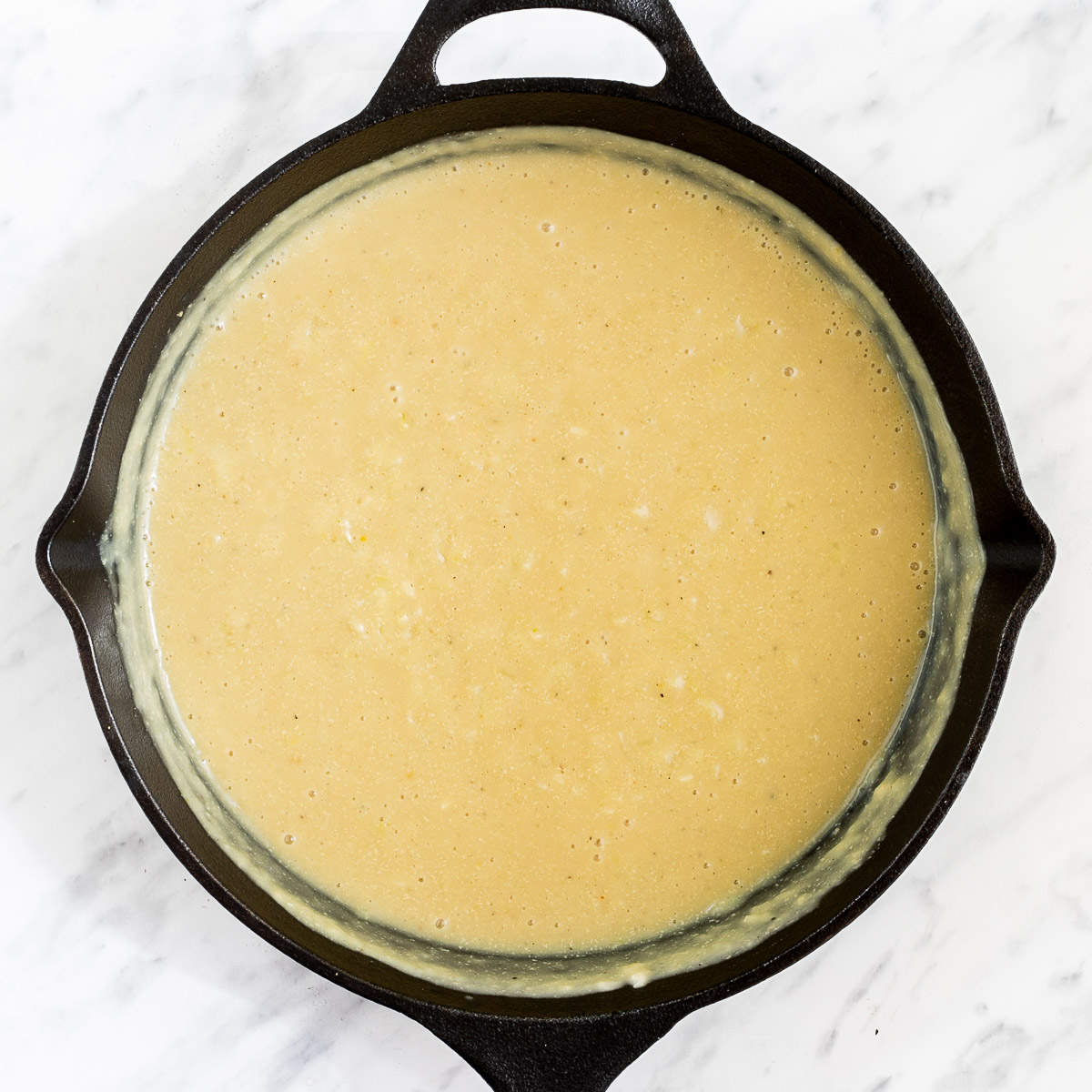 Black cast iron skillet with thick yellow sauce.