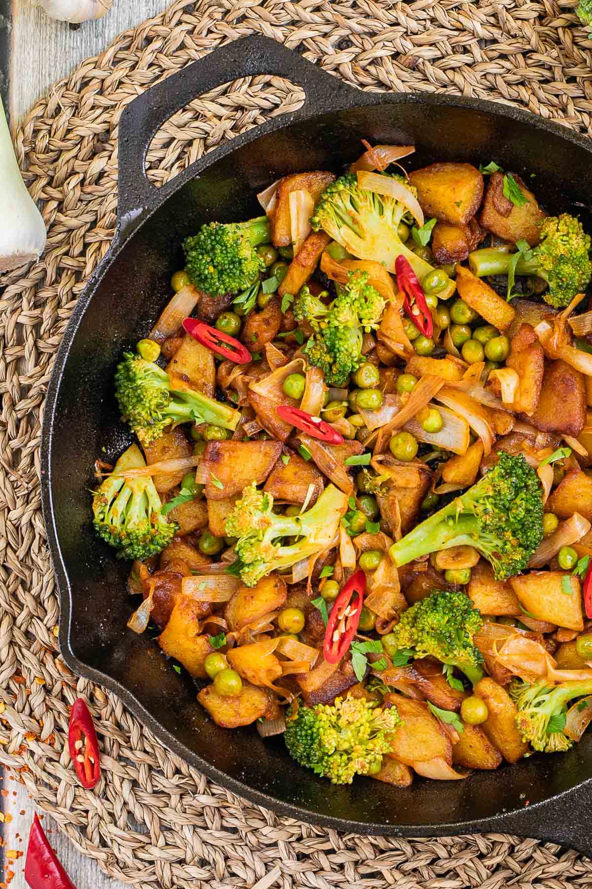 Skillet with potatoes, broccoli, chili peppers, green peas and onion. All slightly fried around the edges.