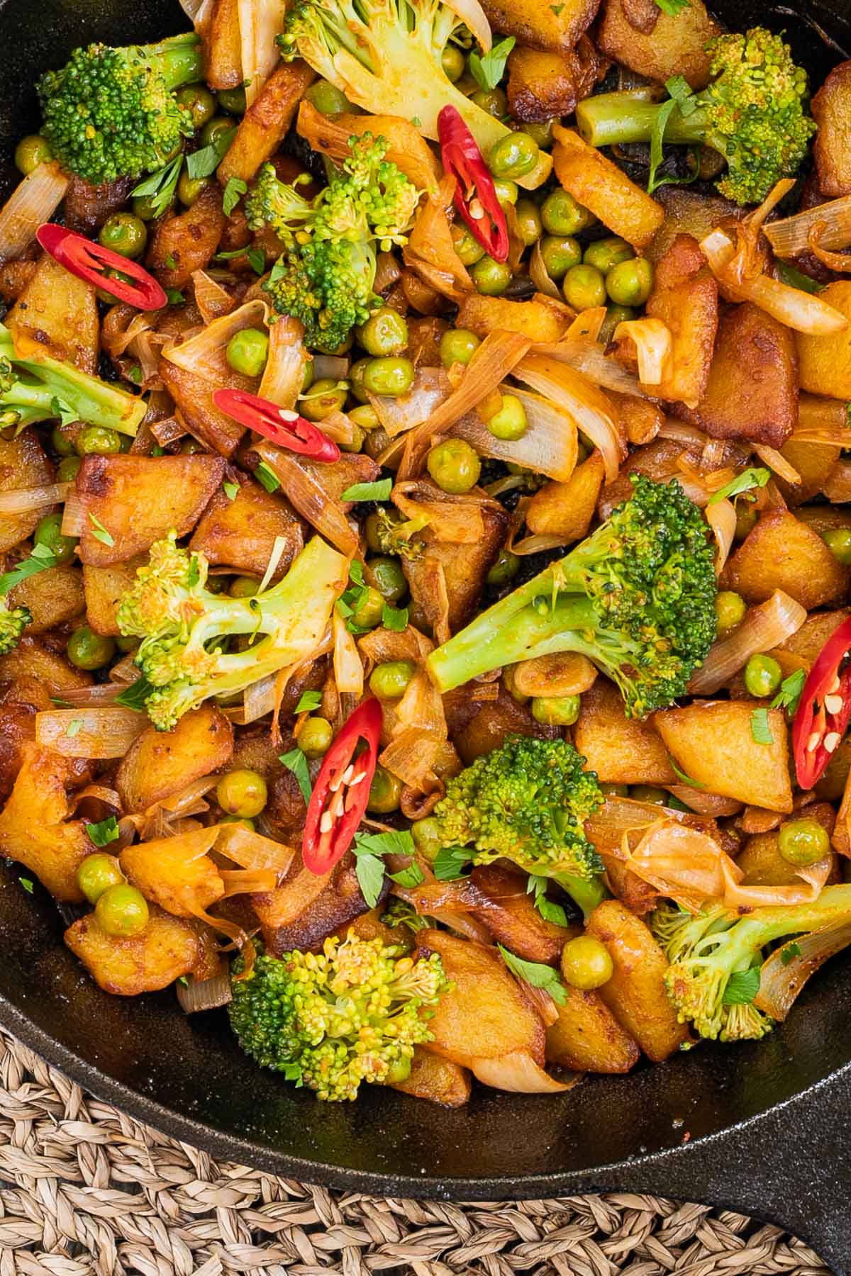Skillet with potatoes, broccoli, chili peppers, green peas and onion. All slightly fried around the edges.