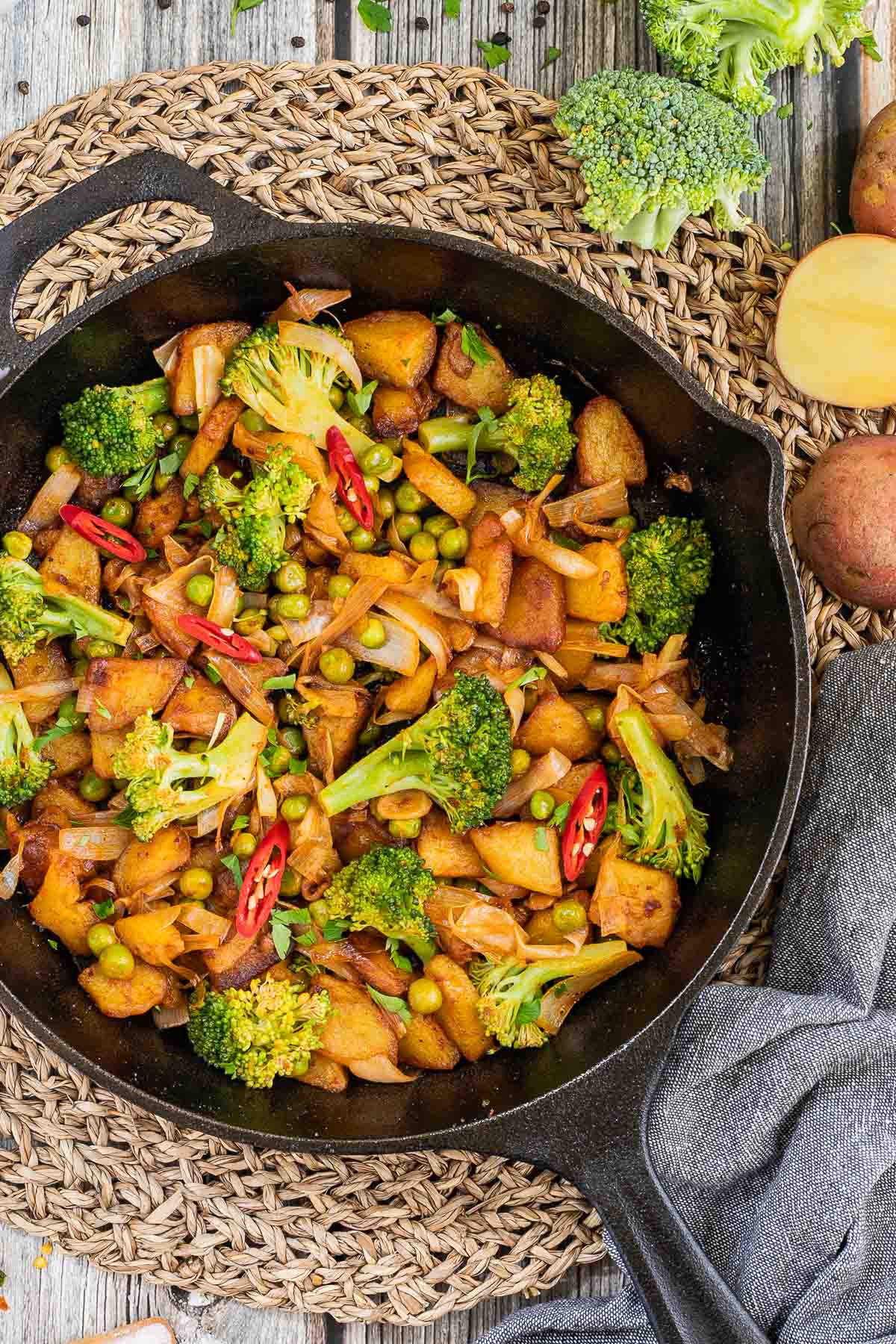 Skillet with potatoes, broccoli, chili peppers, green peas and onion. All slightly fried around the edges.