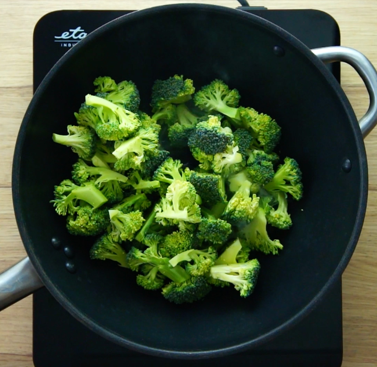 A wok full of vibrant green broccoli florets.