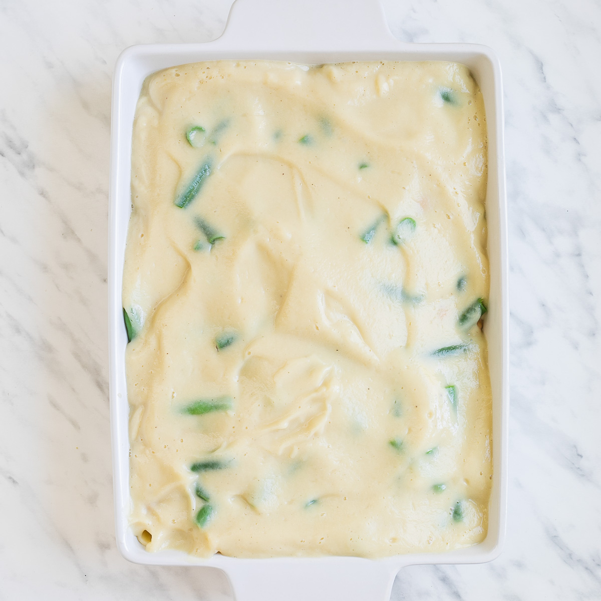 White baking dish full of light brown creamy sauce.