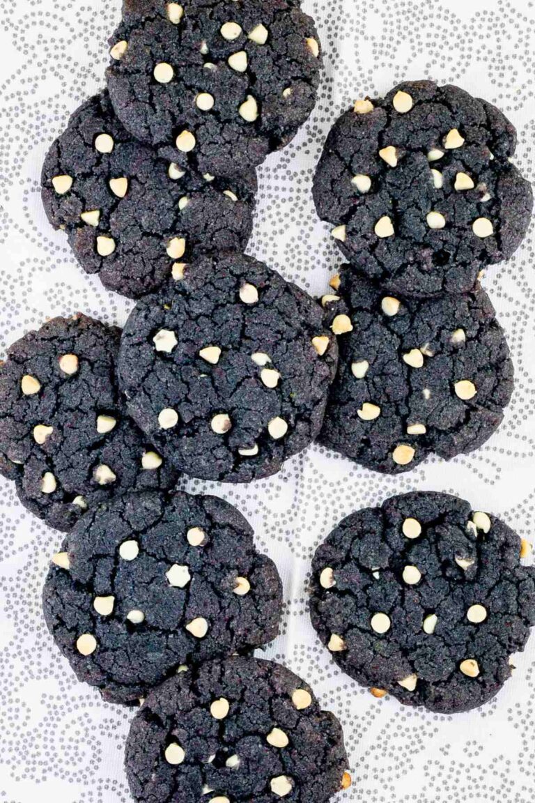 Blue-purple cookies with white chocolate chips on a white-grey surface.