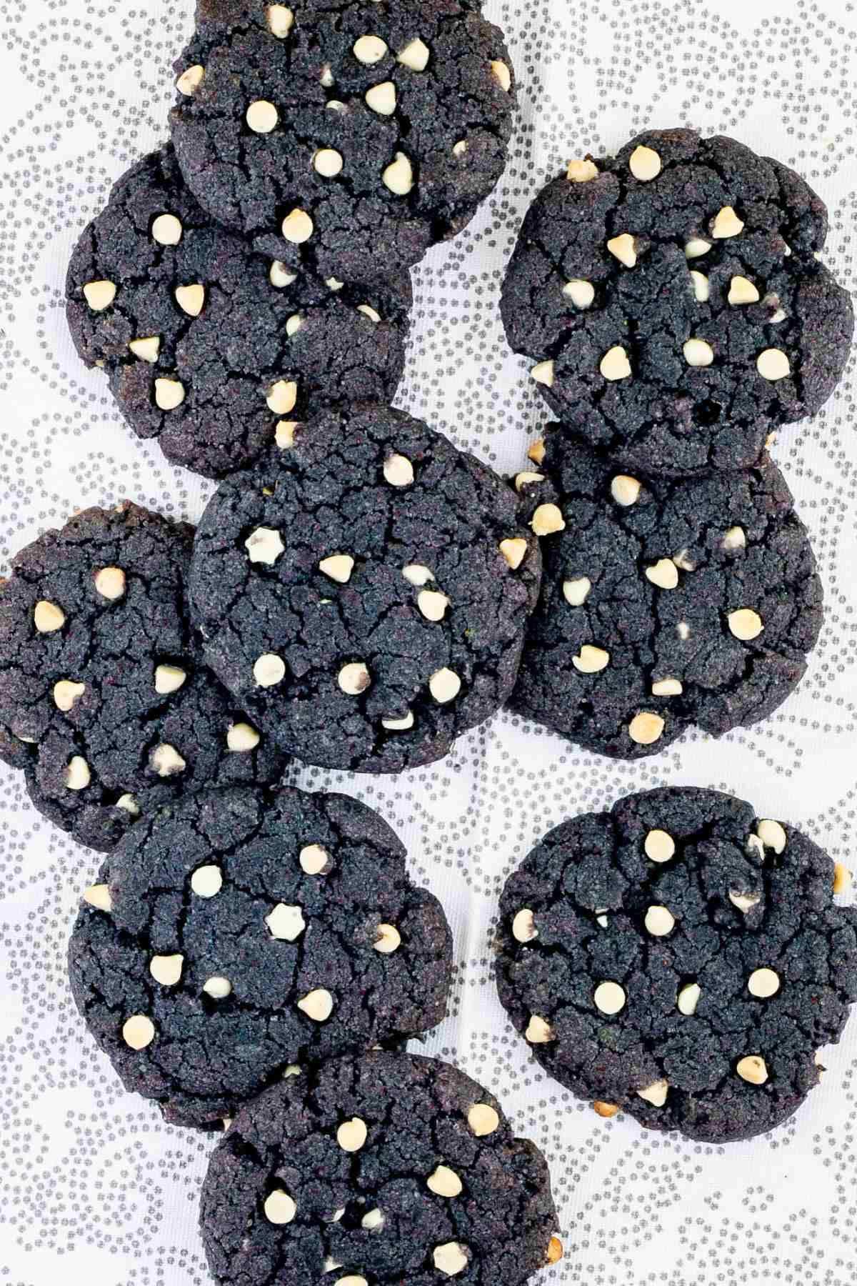 Blue-purple cookies with white chocolate chips on a white-grey surface.