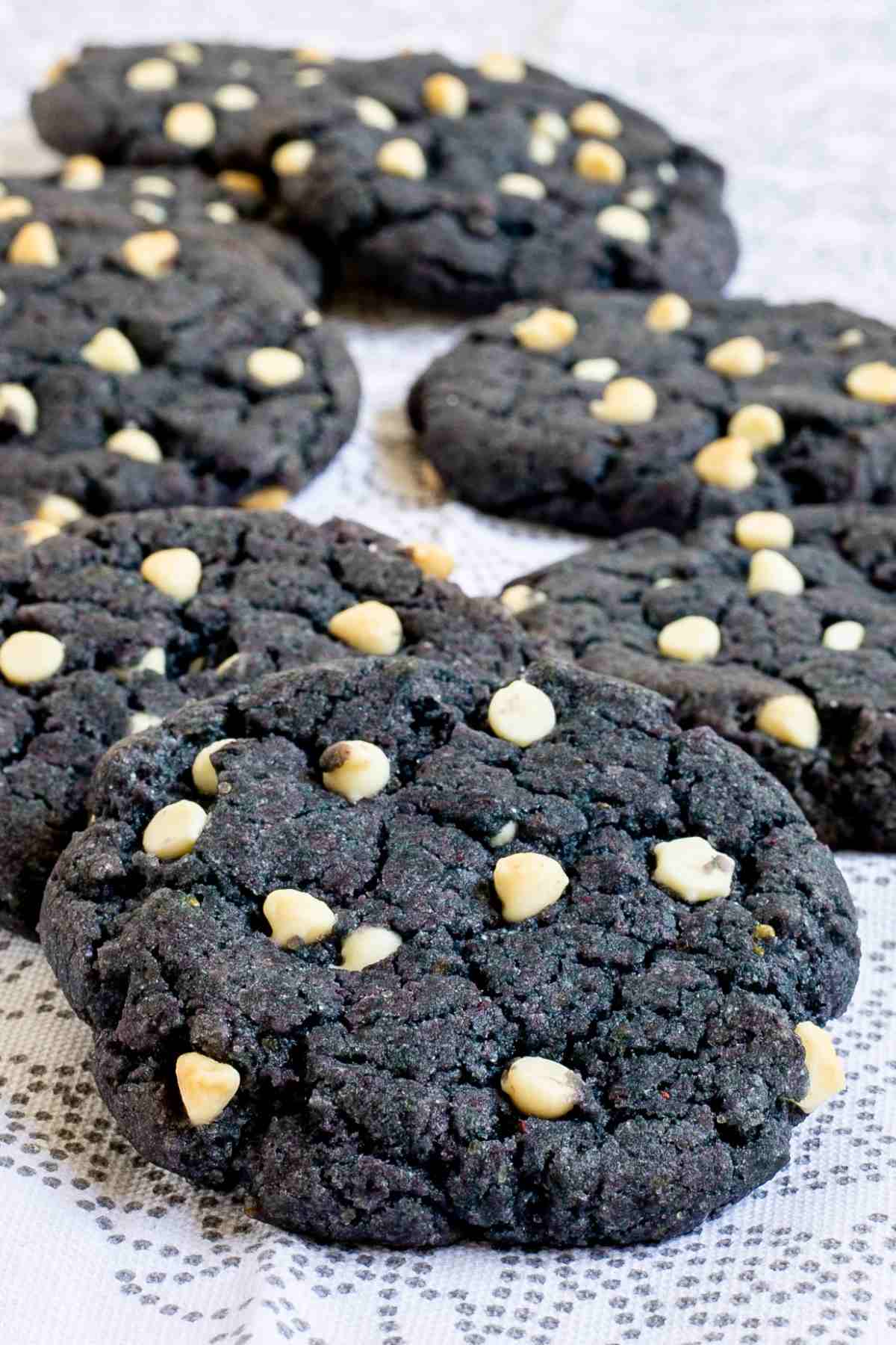 Blue-purple cookies with white chocolate chips on a white-grey surface.