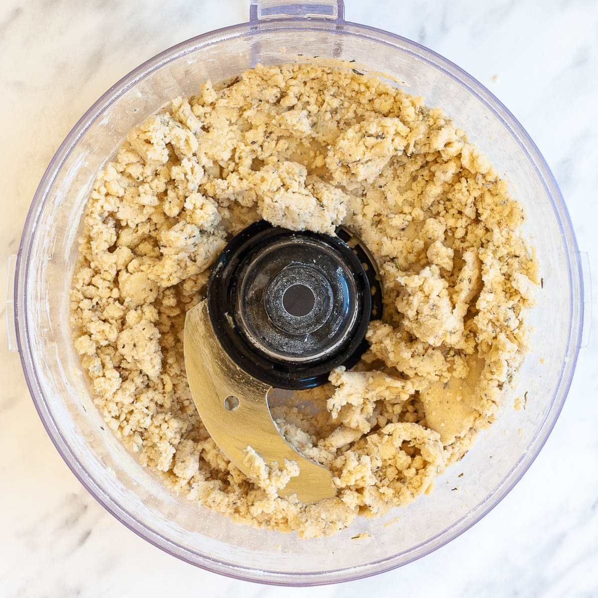 Food processor with a herby light brown pie dough