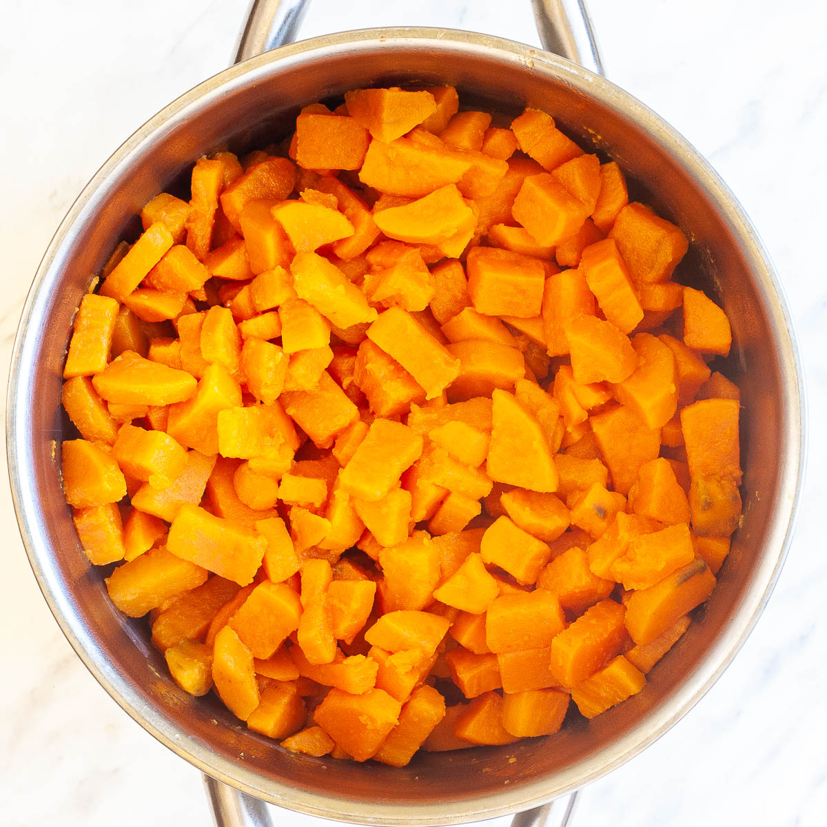 Stockpot with diced cooked orange sweet potatoes.