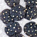 Blue-purple cookies with white chocolate chips on a white-grey surface.
